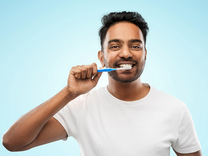 Portrait of a man brushing his tooth with a smile wearing white tshirt